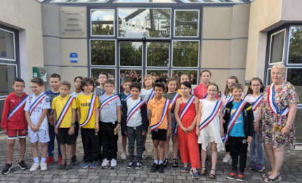 conseil municipal des enfants devant la mairie avec les écharpes tricolores